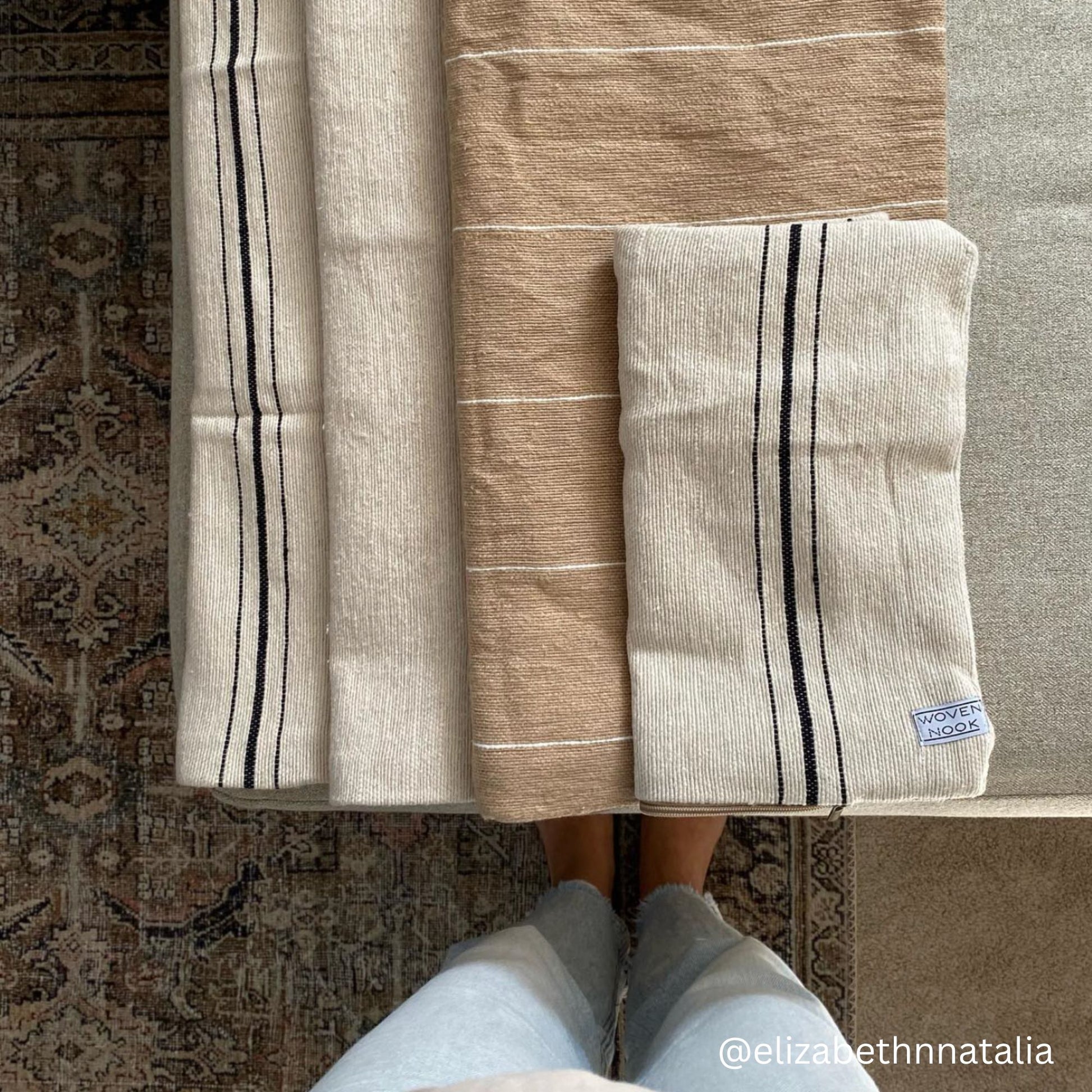 Striped throw blanket in cream and tan with black stripe detail, displayed folded.