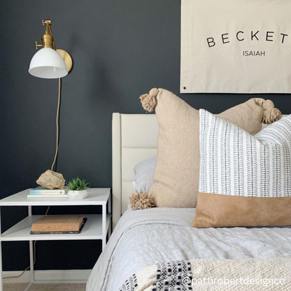 Brass floor lamp with white dome shade and adjustable arm in bedroom setting.