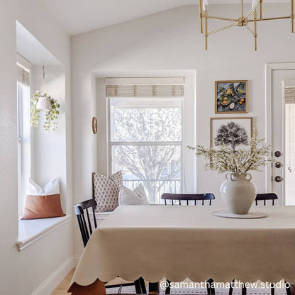 Gold geometric pendant light fixture hanging above white dining table in bright kitchen.